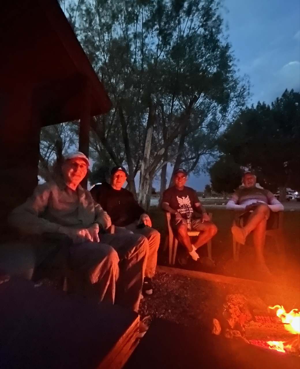Four riders around campfire at dusk