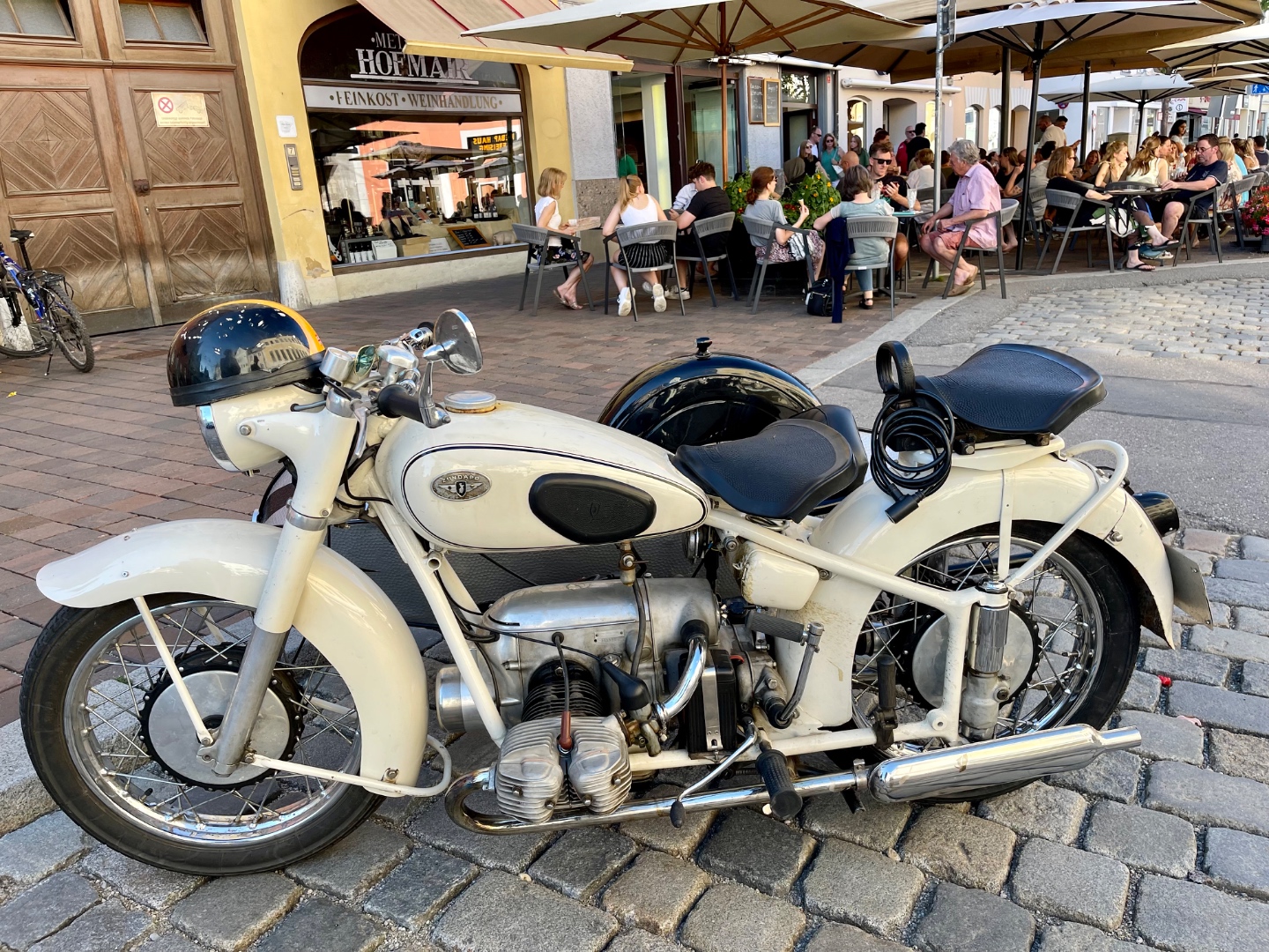 Vintage Zündapp KS 601 motorcycle with sidecar on Bavarian cobblestones, Hofmar wine shop behind
