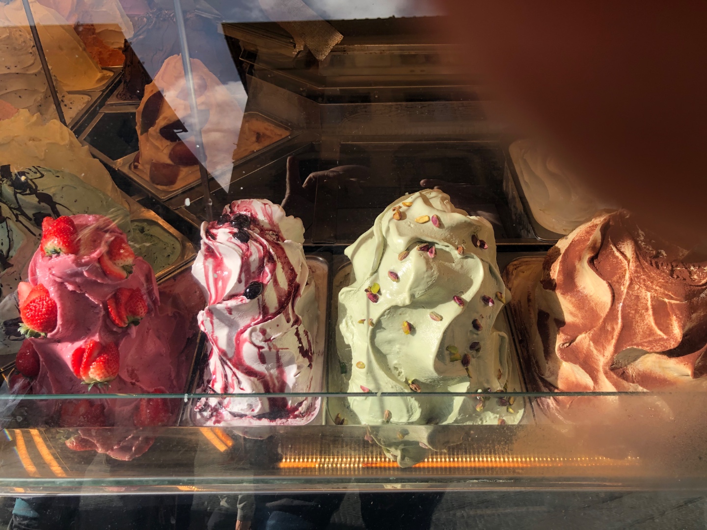 Gelato display case with strawberry, black cherry, pistachio, chocolate flavors at Cinque Terre gelateria