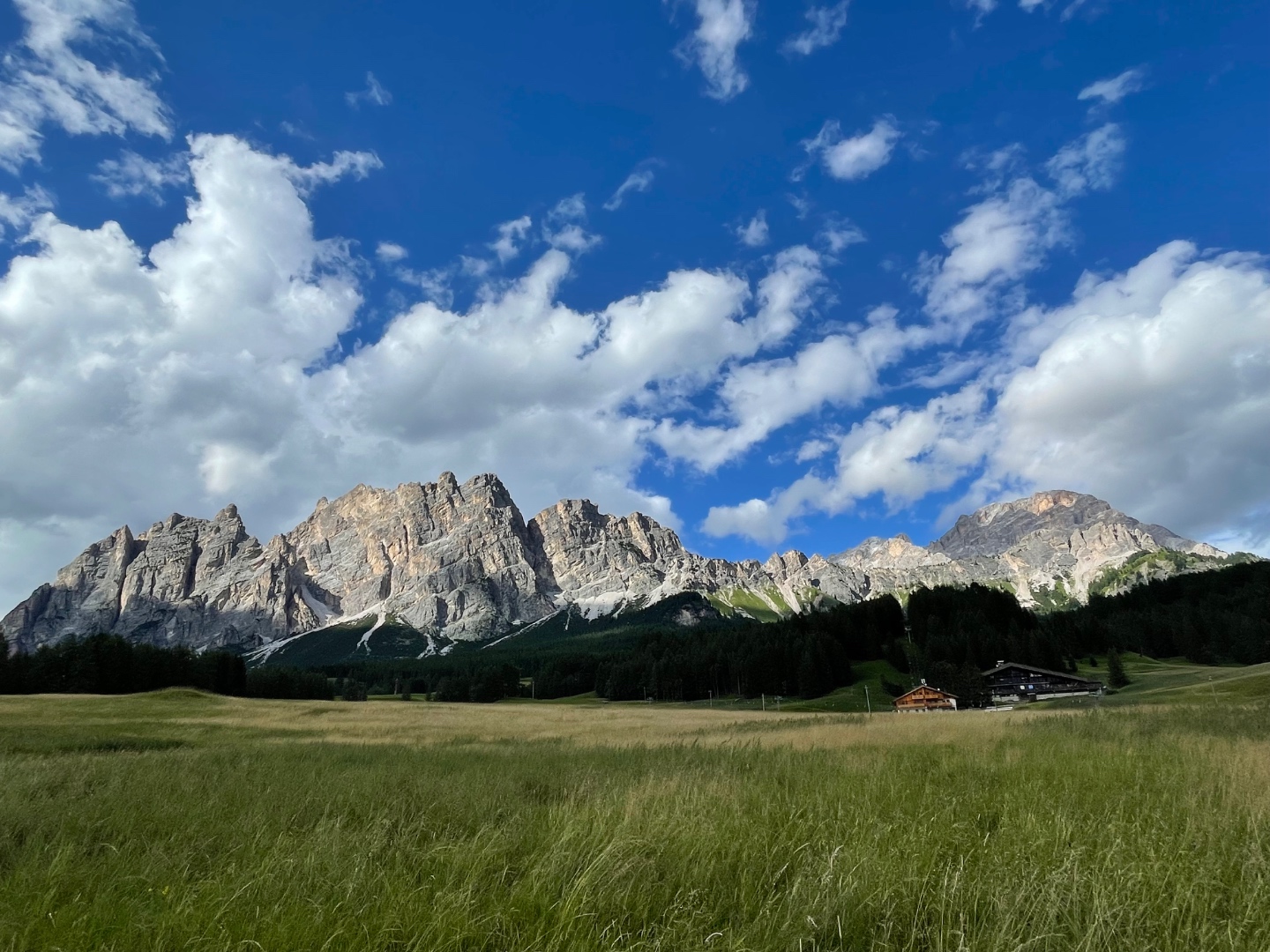 Cristallo massif with golden afternoon light, meadow and chalet, Dolomites Italy