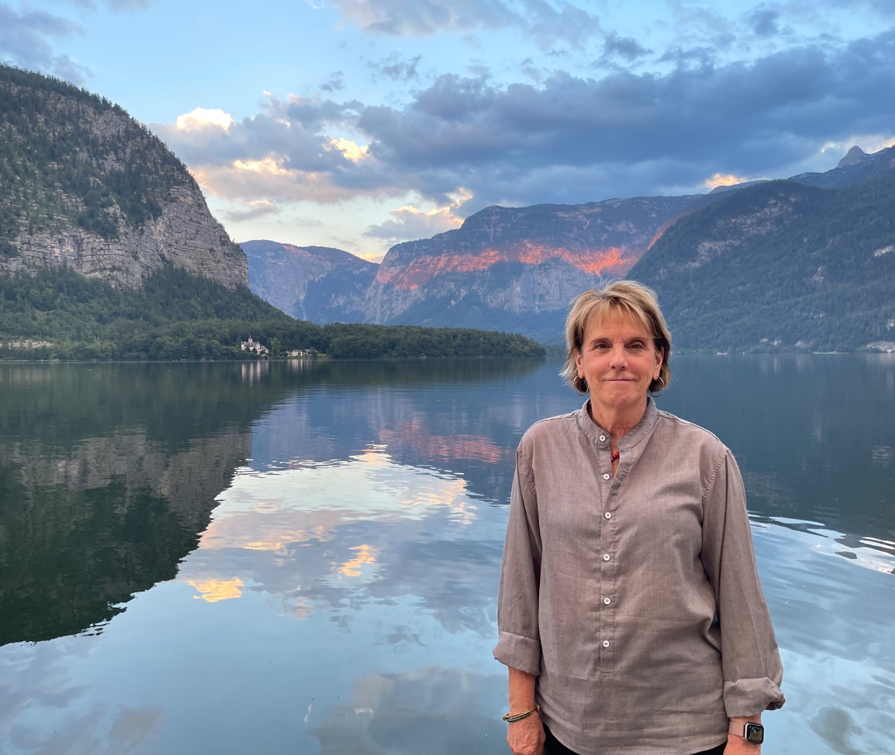 Kathy alone at Hallstatt lake with alpenglow on limestone cliffs behind, Upper Austria