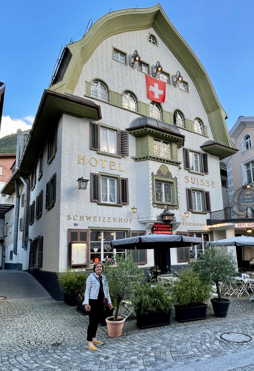 Kathy in front of Hotel Suisse Schweizerhof with Swiss flag flying, Switzerland