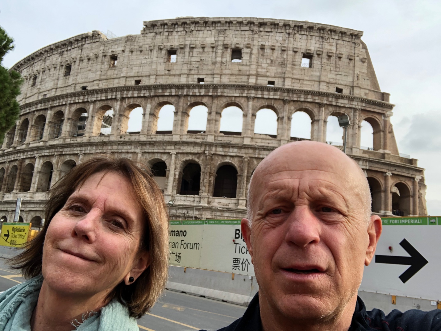 Joe and Kathy selfie at the Colosseum Rome with Roman Forum signs visible