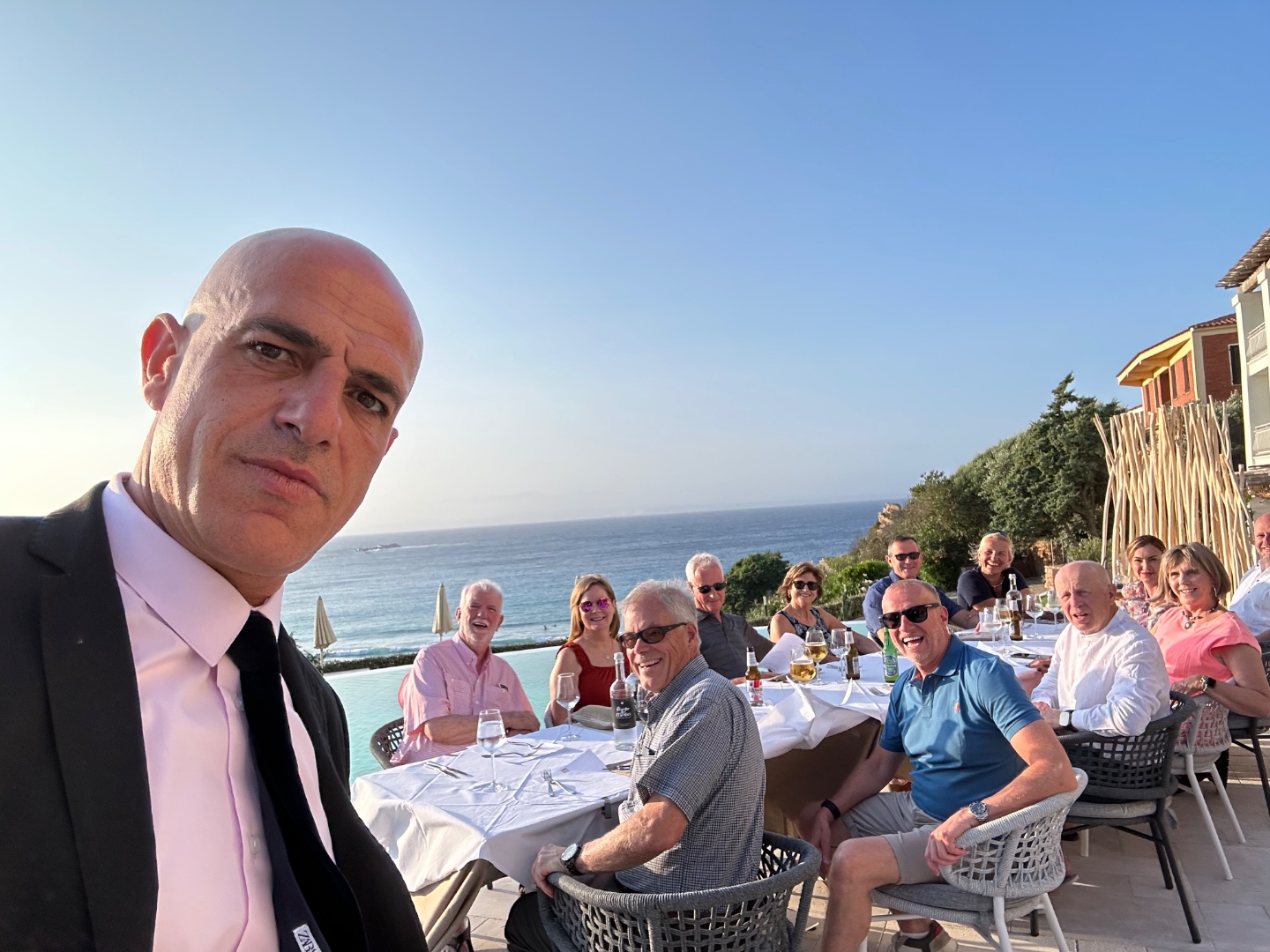 Formally dressed Italian waiter takes selfie with tour group at Sardinia dinner